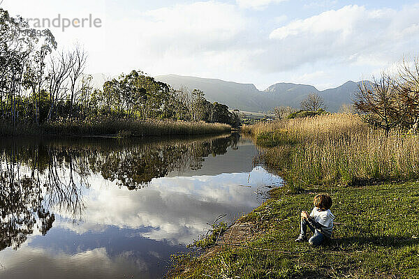 Junger Junge spielt am Flussufer  flaches ruhiges Wasser und offene Flächen