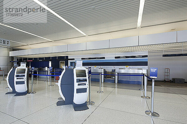 Selbstabfertigungsschalter und traditionelle Gepäckabfertigungsschalter in einem leeren Flughafen.