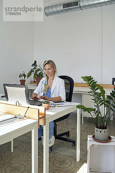 Mittlere erwachsene Geschäftsfrau arbeitet am Laptop im Büro