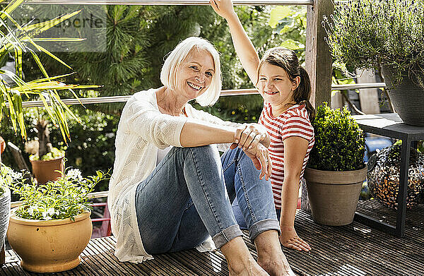 Lächelnde Großmutter sitzt mit Enkelin auf dem Balkon