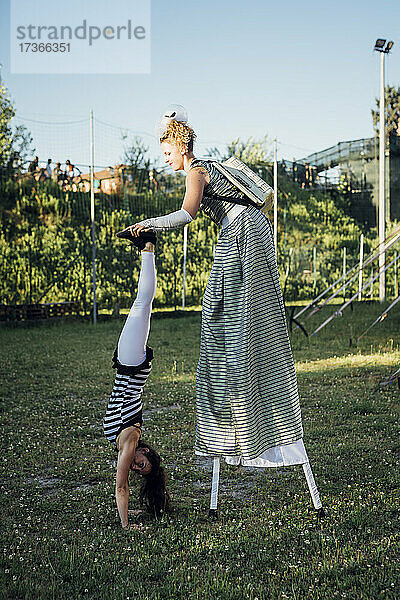 Artistin hilft Akrobatin beim Handstand auf der Wiese