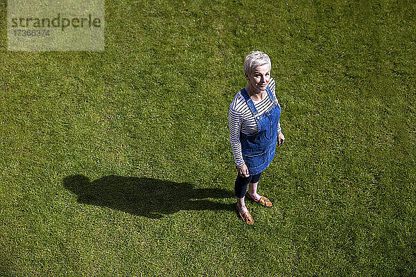 Frau steht auf Gras im Garten an einem sonnigen Tag