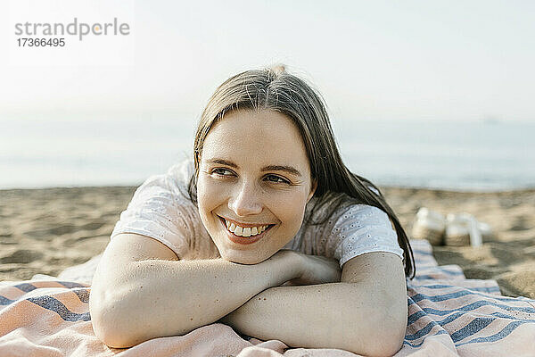 Lächelnde Frau  die auf einem Strandtuch liegt und sich entspannt
