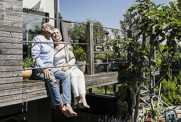 Gelassenes Paar sitzt zusammen auf dem Balkon an einem sonnigen Tag