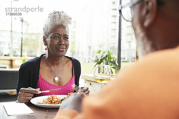 Frau sieht Mann beim Essen im Restaurant an