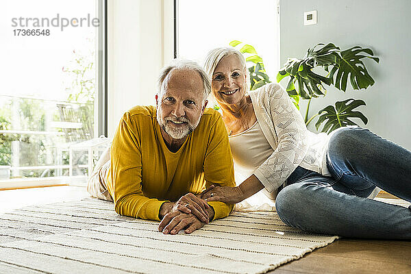 Lächelndes reifes Paar  das zusammen auf einem Teppich zu Hause ruht