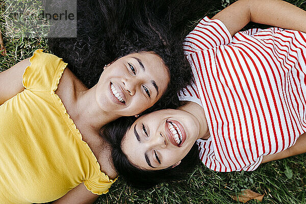 Glückliches lesbisches Paar  das zusammen auf dem Rasen eines Parks liegt