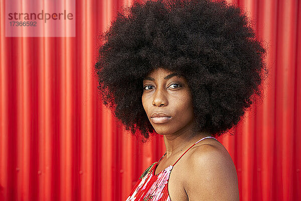 Afro junge Frau an roter Wellblechwand