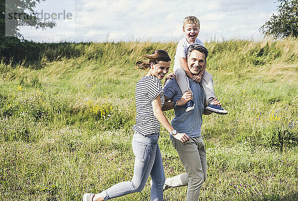 Lächelnde Familie beim gemeinsamen Laufen auf der Wiese