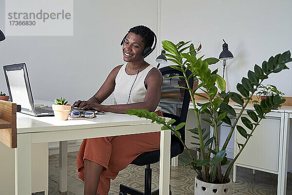 Lächelnde Kundendienstmitarbeiterin bei der Arbeit am Laptop im Büro