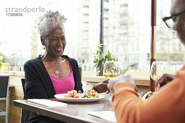 Lächelnde Frau schaut Mann an  während sie im Restaurant sitzt