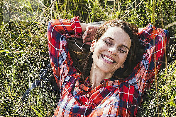 Fröhliche Frau mit geschlossenen Augen im Gras liegend