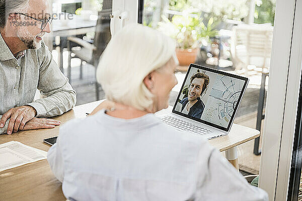 Männliche und weibliche Geschäftsleute führen ein Videogespräch mit einem Kollegen auf einem Laptop im Heimbüro