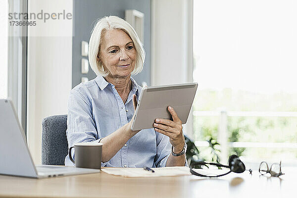 Geschäftsfrau mit digitalem Tablet am Schreibtisch im Heimbüro