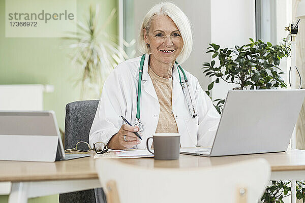 Lächelnde reife Ärztin am Schreibtisch
