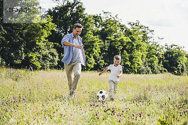 Fröhlicher Vater und Sohn spielen Fußball auf dem Rasen