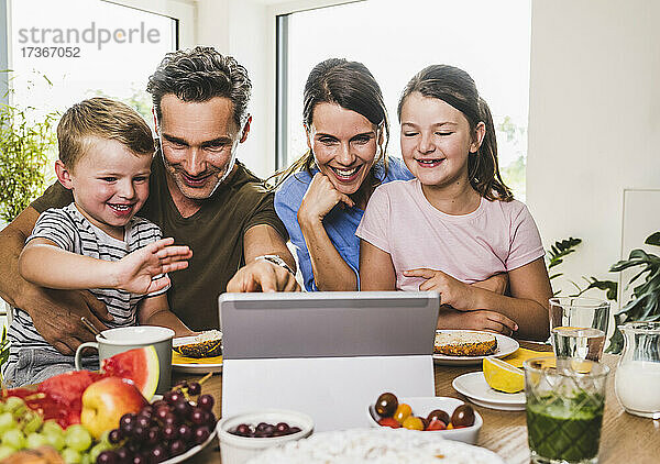 Lächelnde Familie gestikuliert während eines Videoanrufs auf dem Laptop zu Hause