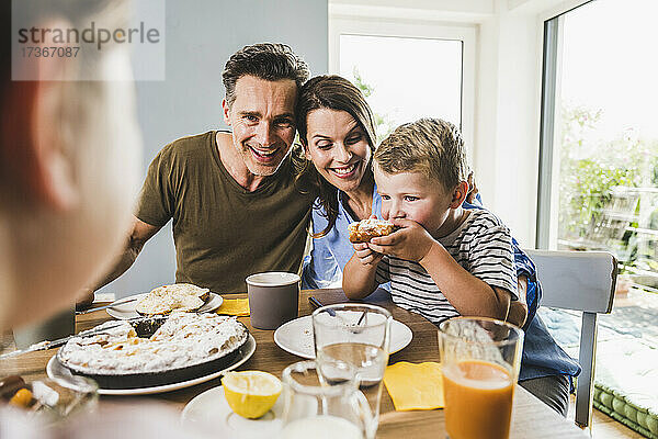 Mann mit Frau sieht Sohn beim Frühstück Kuchen essen