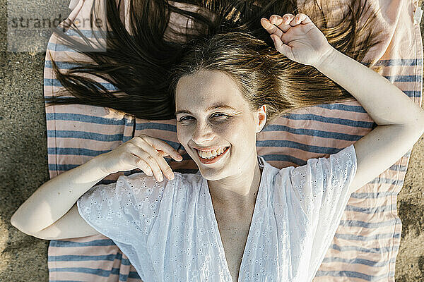 Lächelnde Frau auf Strandtuch liegend
