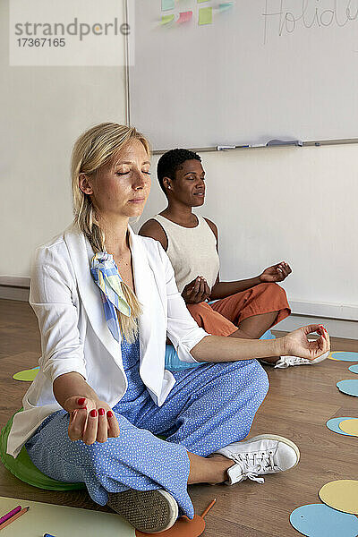 Geschäftsfrau macht Yoga mit Kollegen im Büro
