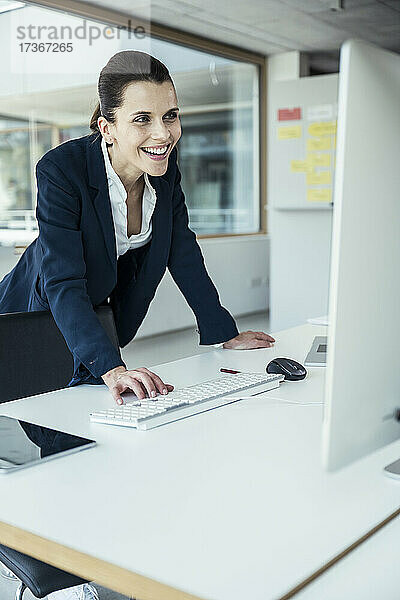 Lächelnde Geschäftsfrau  die einen Computer bei der Arbeit im Büro benutzt