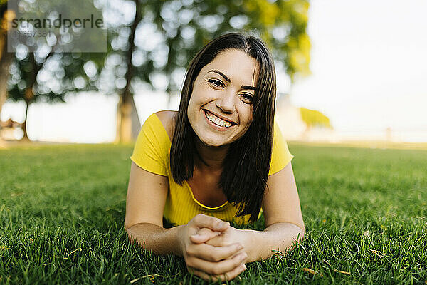 Glückliche junge Frau entspannt sich auf Gras im Park