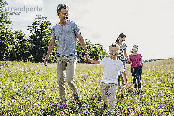 Eltern  die ihre Kinder an der Hand halten  während sie über den Rasen laufen
