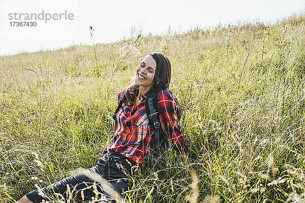 Lächelnde Frau entspannt sich beim Sitzen auf der Wiese