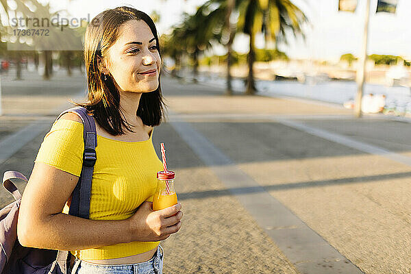 Junge Frau mit Orangensaft auf der Straße stehend