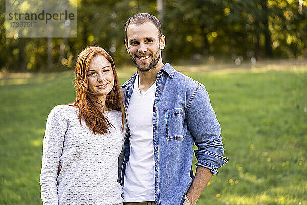 Porträt eines lächelnden jungen Paares bei einem Spaziergang in einem Park