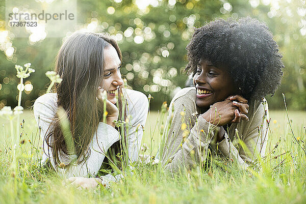 Porträt von lächelnden jungen Freundinnen  die im Park liegen