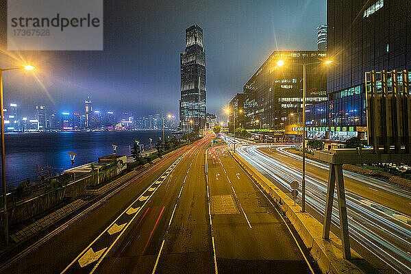 Langzeitbelichtung des fließenden Verkehrs auf einer Stadtstraße mit Wohngebäuden im Hintergrund  Hongkong