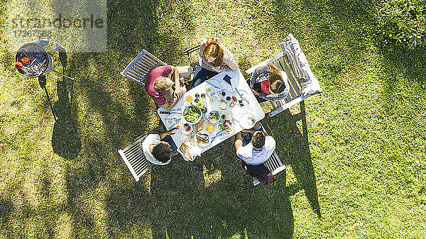 Glückliche junge Freunde beim Essen an einem Tisch im Garten