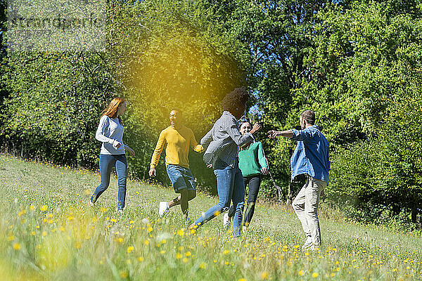 Glückliche junge Freunde haben Spaß beim gemeinsamen Laufen im Park