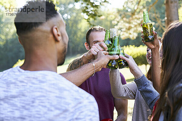 Junge Freunde trinken Bier  während sie im Park stehen