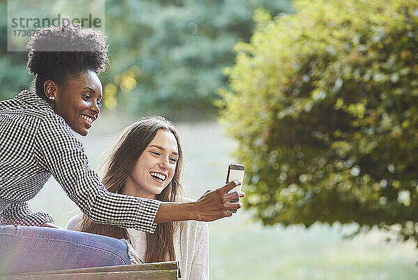 Lächelnde junge Freunde machen ein Selfie mit ihrem Smartphone