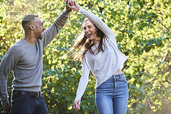 Lächelndes junges Paar tanzt im öffentlichen Park