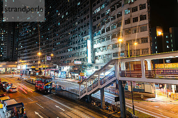 Ansicht eines Gebäudes und von Geschäften mit einem Fahrzeug  das sich auf der Straße bewegt  Hongkong