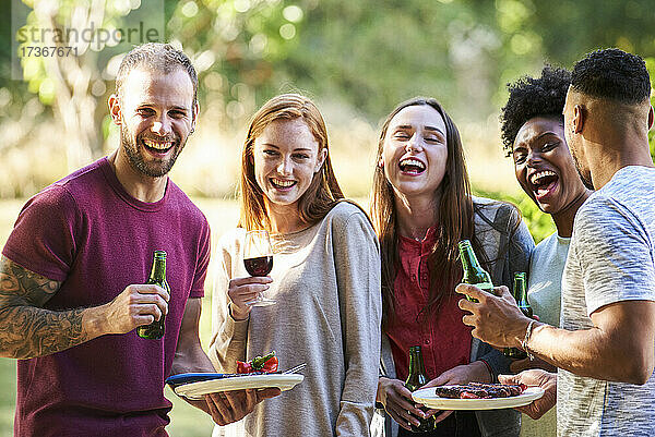 Glückliche junge Freunde beim Essen und Trinken im Park