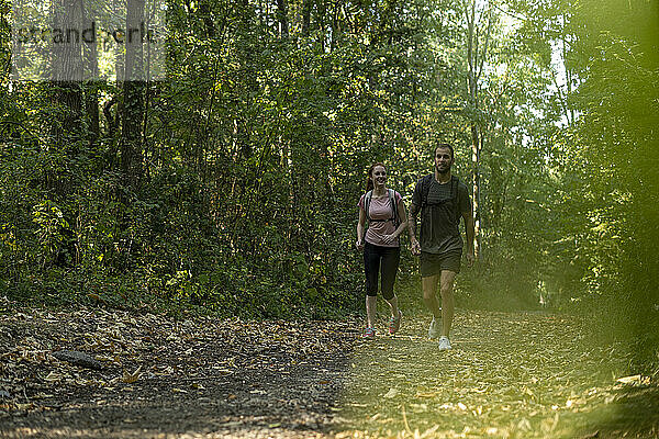 Lächelndes junges Paar beim Spaziergang im Wald