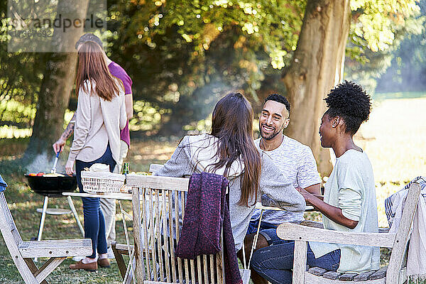 Lächelnde junge Freunde beim Essen am Tisch im Garten