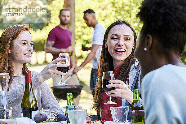 Lächelnde junge Frauen bei Wein und Bier im Park