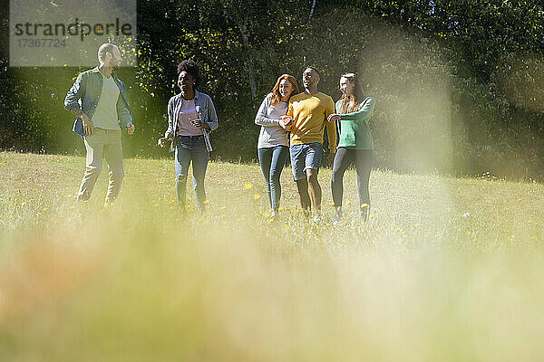 Glückliche junge Freunde haben Spaß beim gemeinsamen Laufen im Park