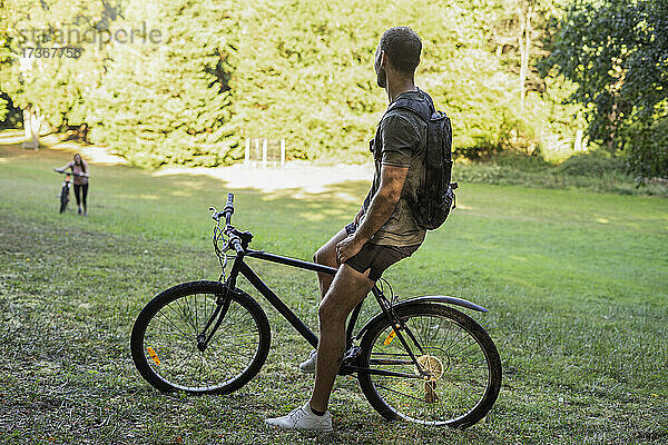 Junger Mann sitzt auf einem Fahrrad und entspannt sich im Wald
