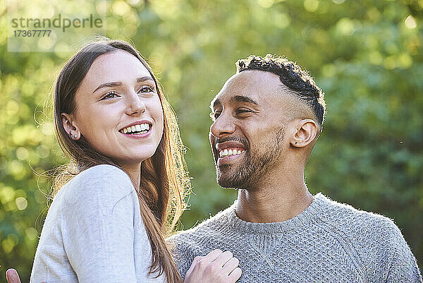 Lächelndes junges Paar im öffentlichen Park sitzend