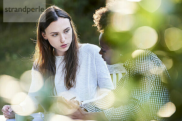 Junge Freundinnen benutzen ein digitales Tablet beim Lernen im Park