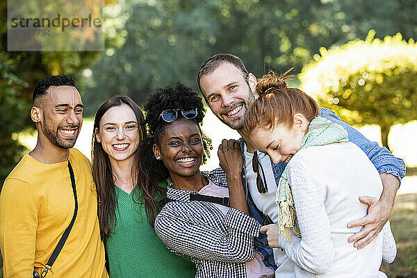 Porträt von jungen Freunden  die in einem öffentlichen Park für ein Foto posieren