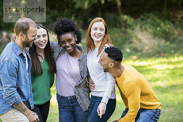 Lächelnde Gruppe von Freunden  die Spaß in einem öffentlichen Park haben
