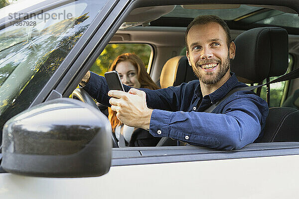 Lächelndes junges Paar genießt die Autofahrt