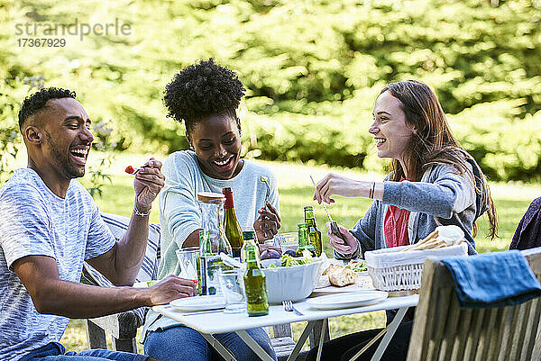 Lächelnde junge Freunde beim Essen im Park